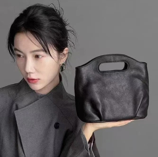 American retro vegan leather crossbody bag in black — lifestyle shot held by woman in grey blazer