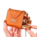 Velvet Matte Lipstick Gift Set 5-Piece orange leather chain bag with gold arch handle and circular charm hand holding bag and their hand removing lipstick from side slot