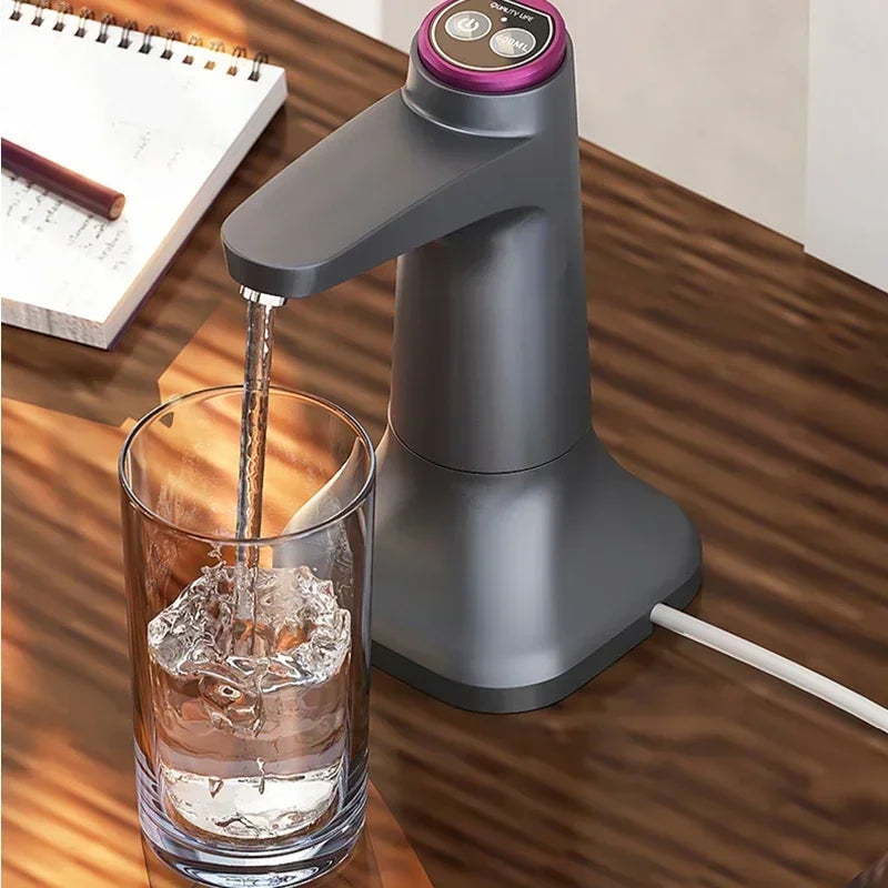 Grey electric water pump pouring water into a glass on a timber desk