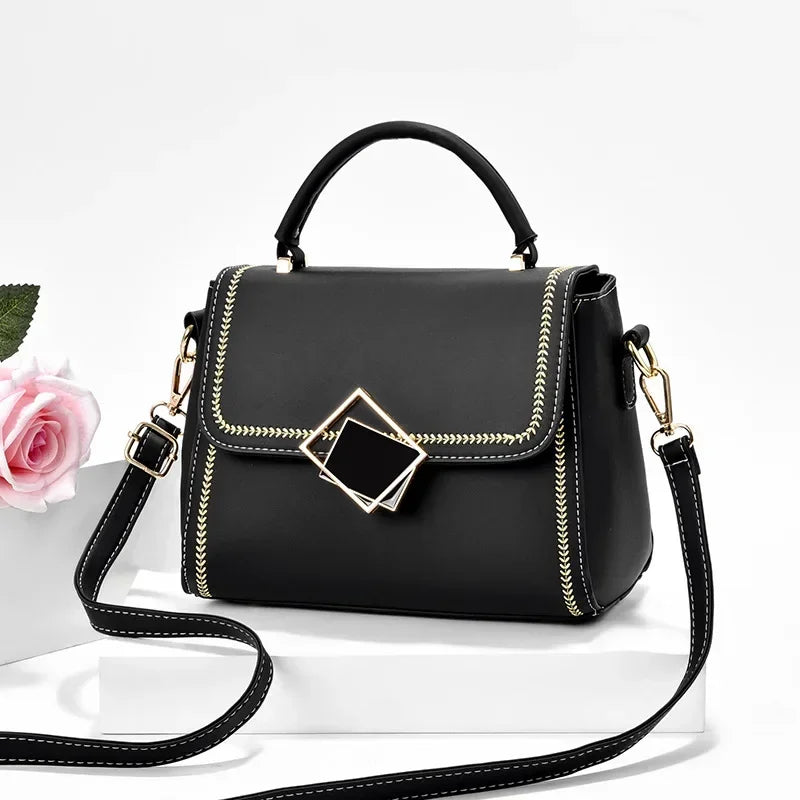 Black PU leather shoulder bag with white feather stitching detail gold metal top handle and geometric clasp