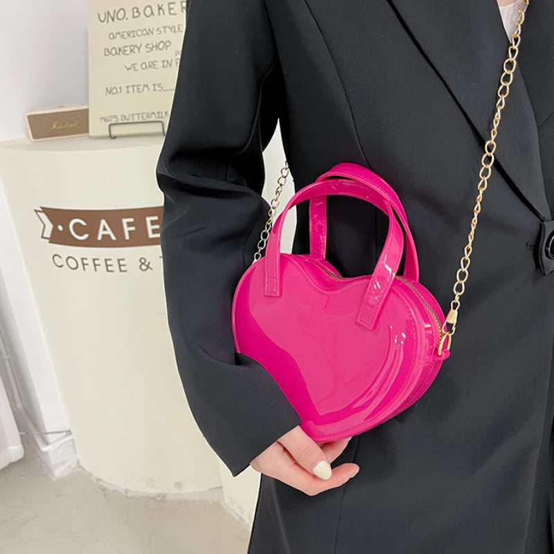 Rose Pink heart-shaped bag worn crossbody with the gold chain strap