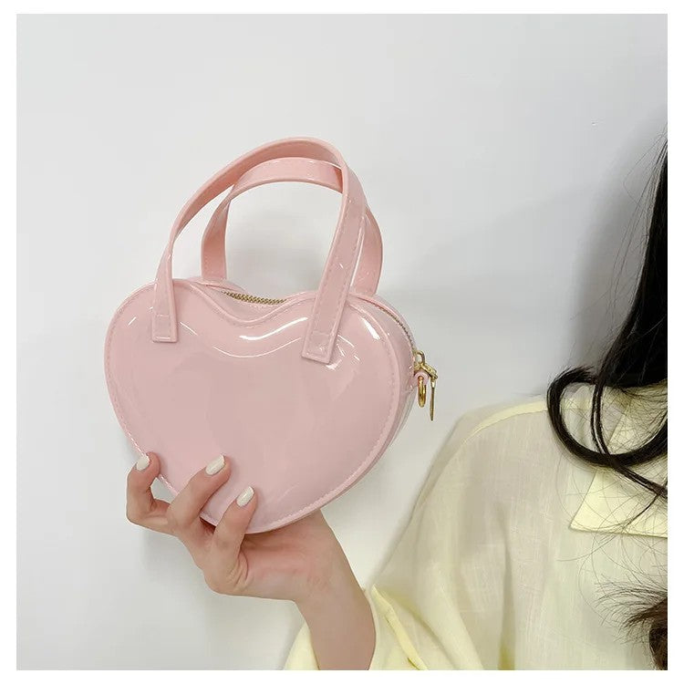Soft pink heart-shaped handbag held up by its twin handles