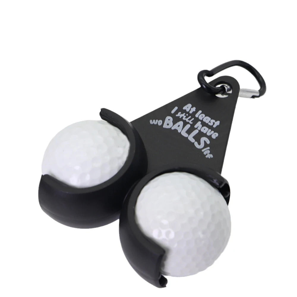 Novelty golf ball holder with carabiner clip holding two white golf balls showing "At least I still have two BALLS left" quote