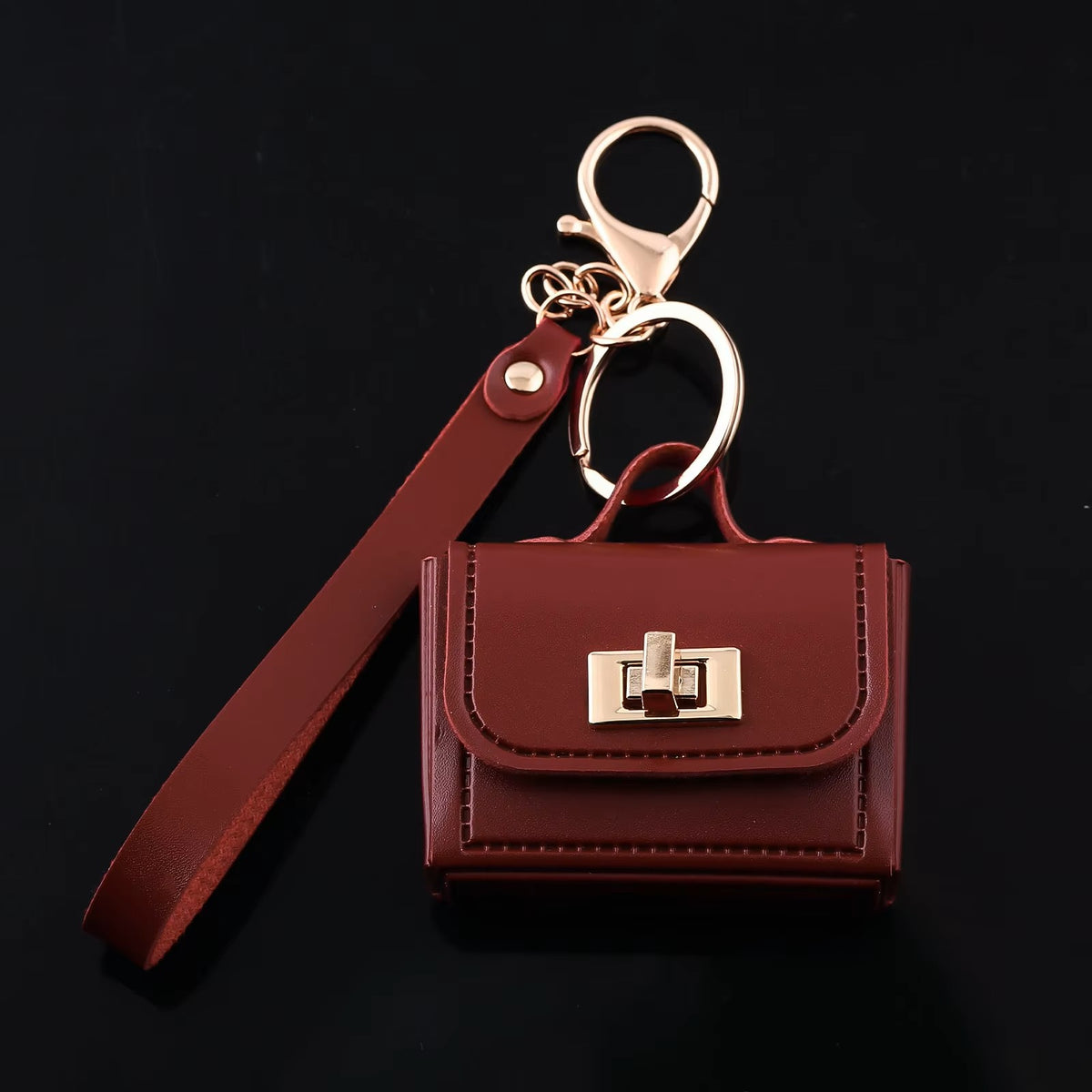 Red kawaii mini bag charm keychain with gold turn-lock and wrist strap on wooden surface
