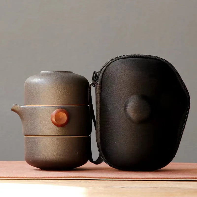 MiniSolutions dark grey ceramic travel tea set with teapot and cup stacked beside its black zip carry case on a wooden surface