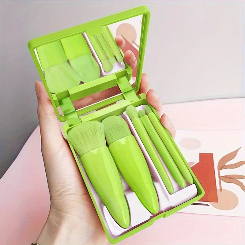 Hand holding open green mini travel makeup brush set with 5 brushes and built-in mirror — portable makeup kit