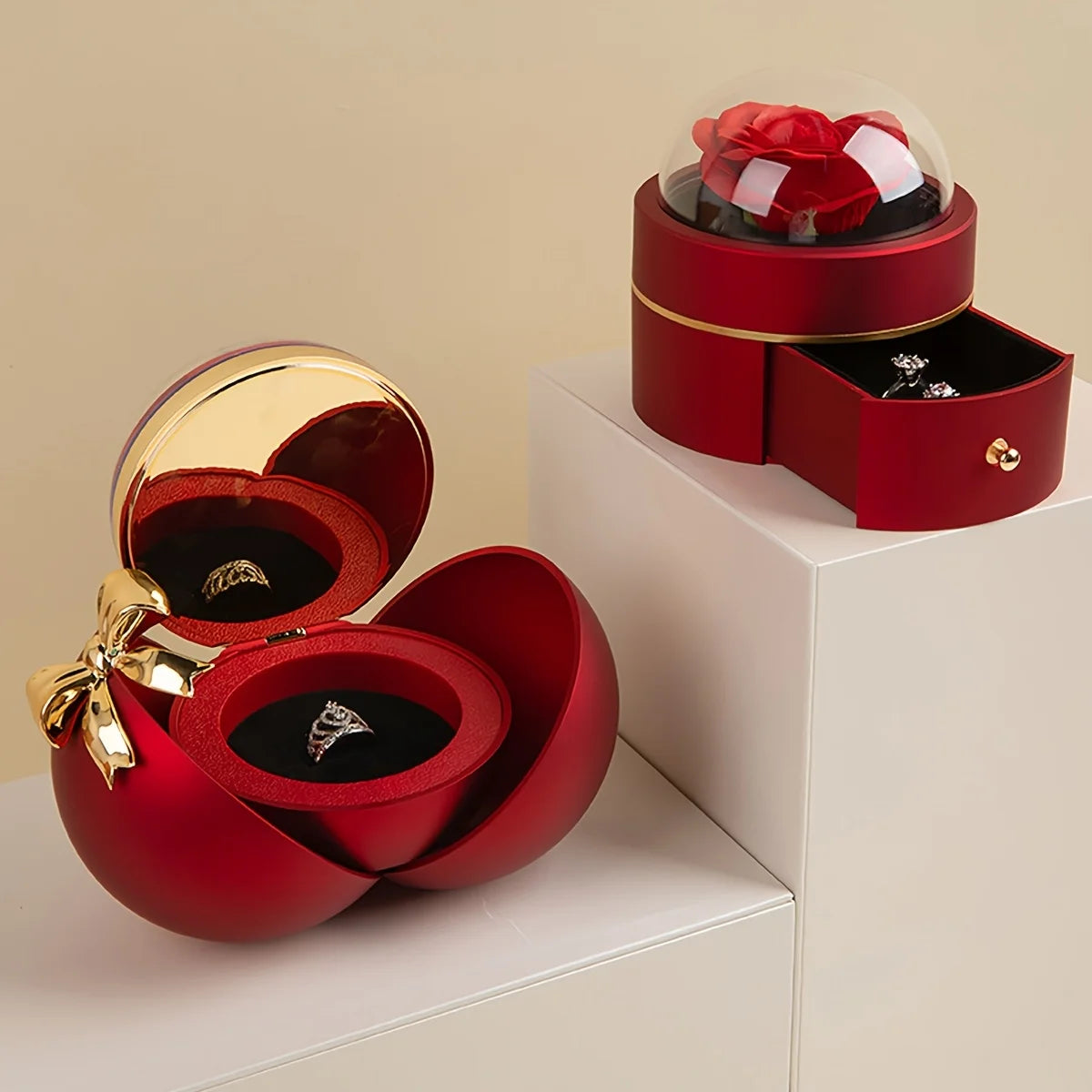 Red jewellery gift box set: a split-open ball box revealing a rose dome with rings inside, beside a round dome box with its drawer open holding earrings