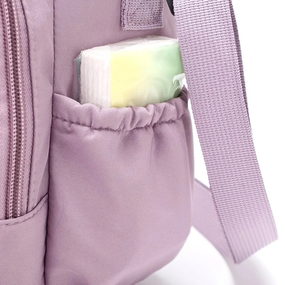 Insulated water bottle bag in pink side view showing elastic side slip pocket holding a packet of tissues with adjustable strap and black clip hardware
