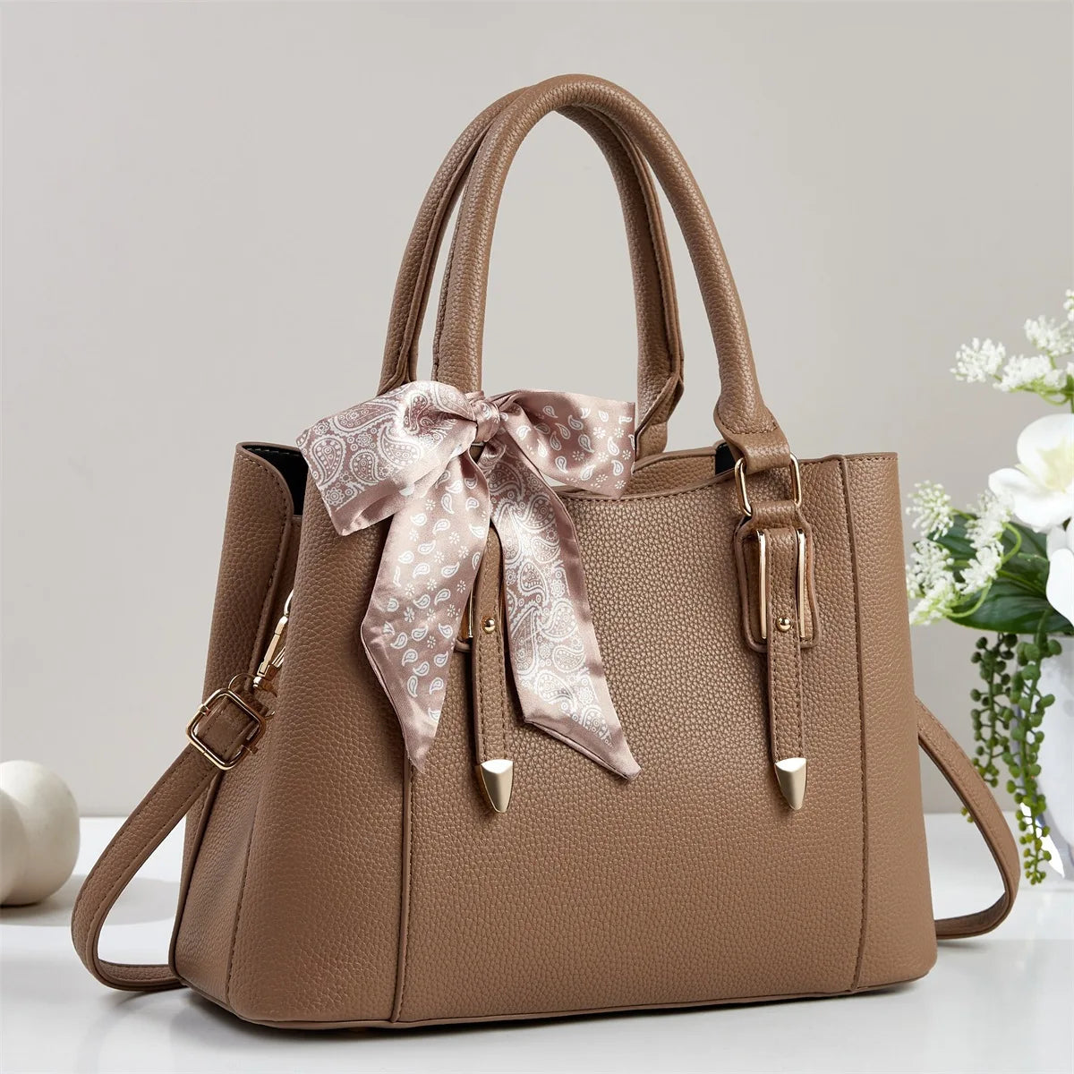 Brown women's soft square shoulder bag with paisley scarf tie detail and gold hardware, crossbody strap