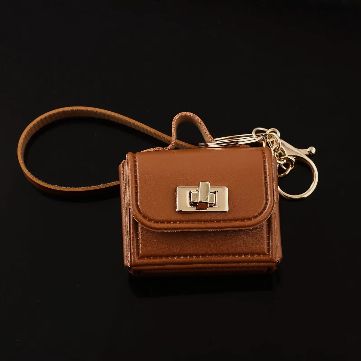 Brown kawaii mini bag charm keychain with gold turn-lock clasp and lobster clasp on black background