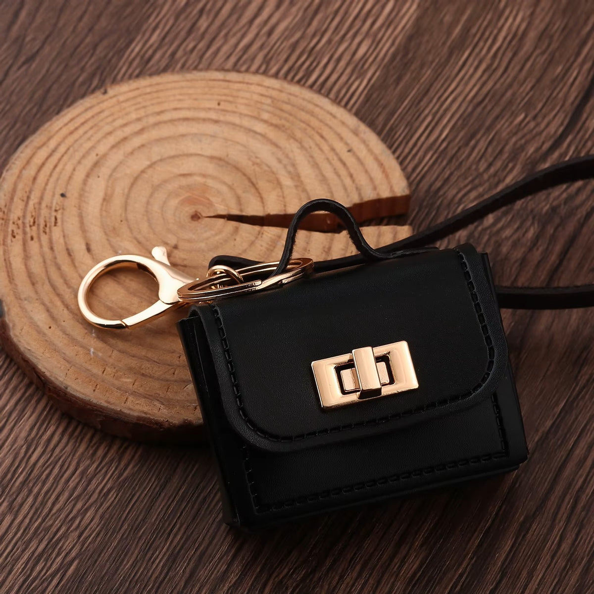 Black kawaii mini bag charm keychain with gold turn-lock clasp on wooden slice — Korean bag pendant