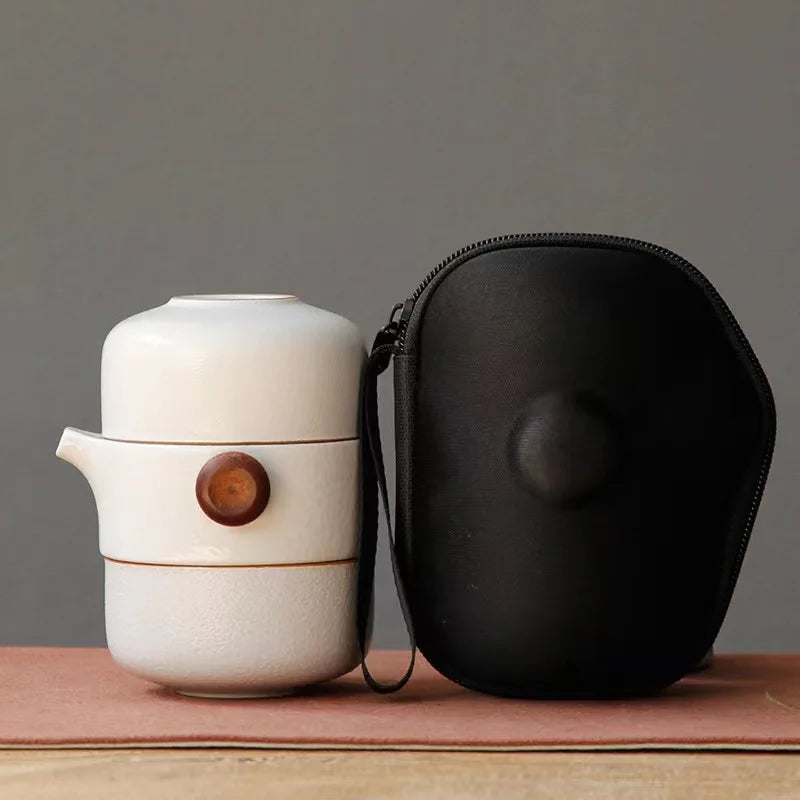 MiniSolutions white ceramic travel tea set with teapot and cup stacked beside its black zip carry case on a wooden surface