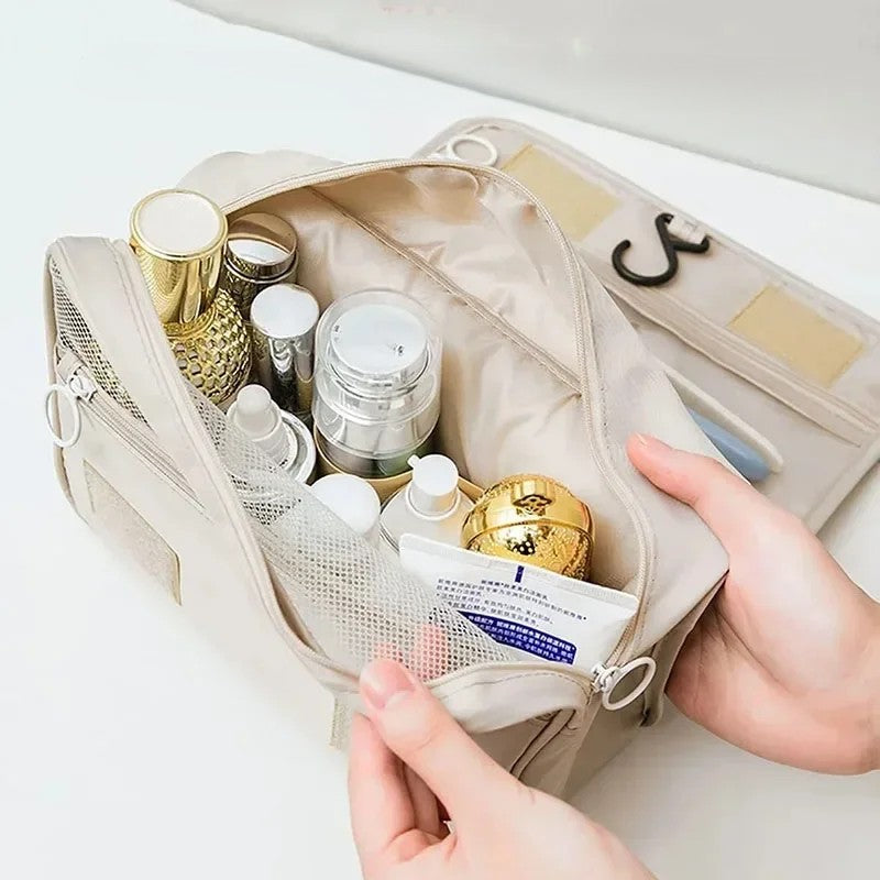 Waterproof travel makeup bag open showing transparent zip compartment, mesh pocket, and main compartment with toiletries