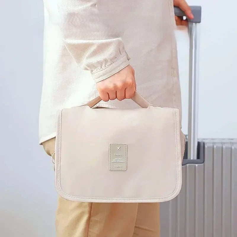 Woman carrying waterproof travel makeup bag by sturdy handle next to luggage