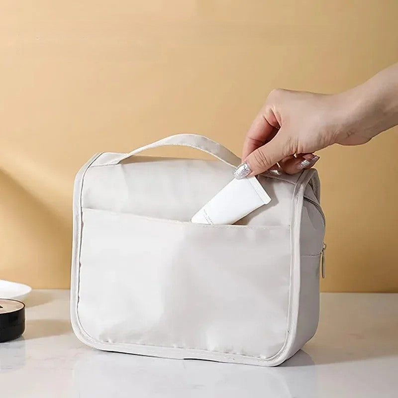 Hand placing toiletry tube into back pocket of waterproof travel makeup bag
